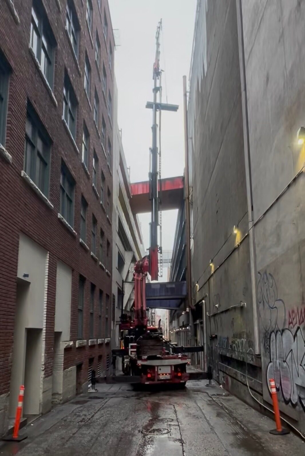 CraneX knuckle boom crane lifting in a narrow alley between two buildings