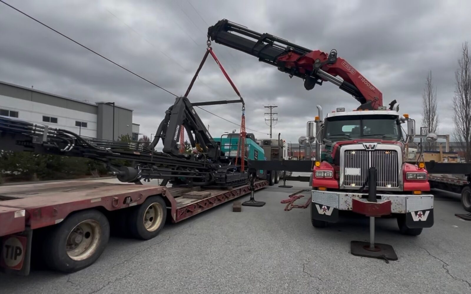 CraneX low bed trailer loaded with heavy equipment being offloaded