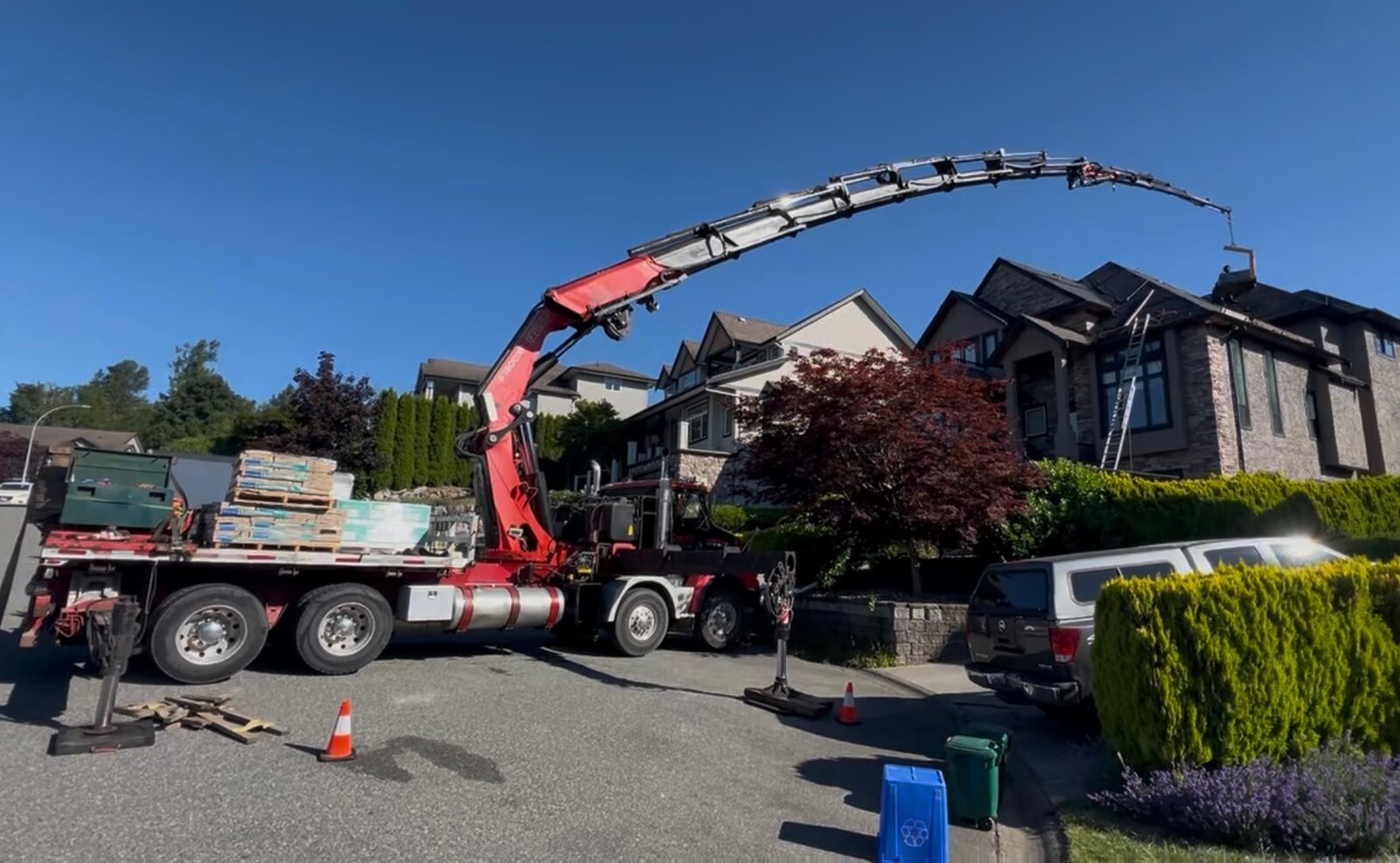 CraneX picker truck hoisting roofing material onto a building roof
