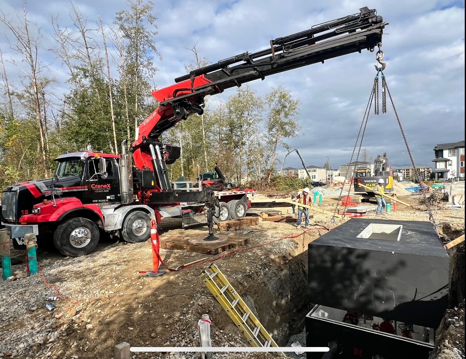 CraneX picker truck lowering a precast concrete utility vault into place