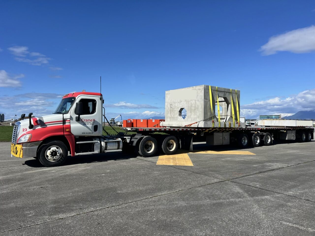 CraneX flat deck truck hauling a heavy precast concrete vault