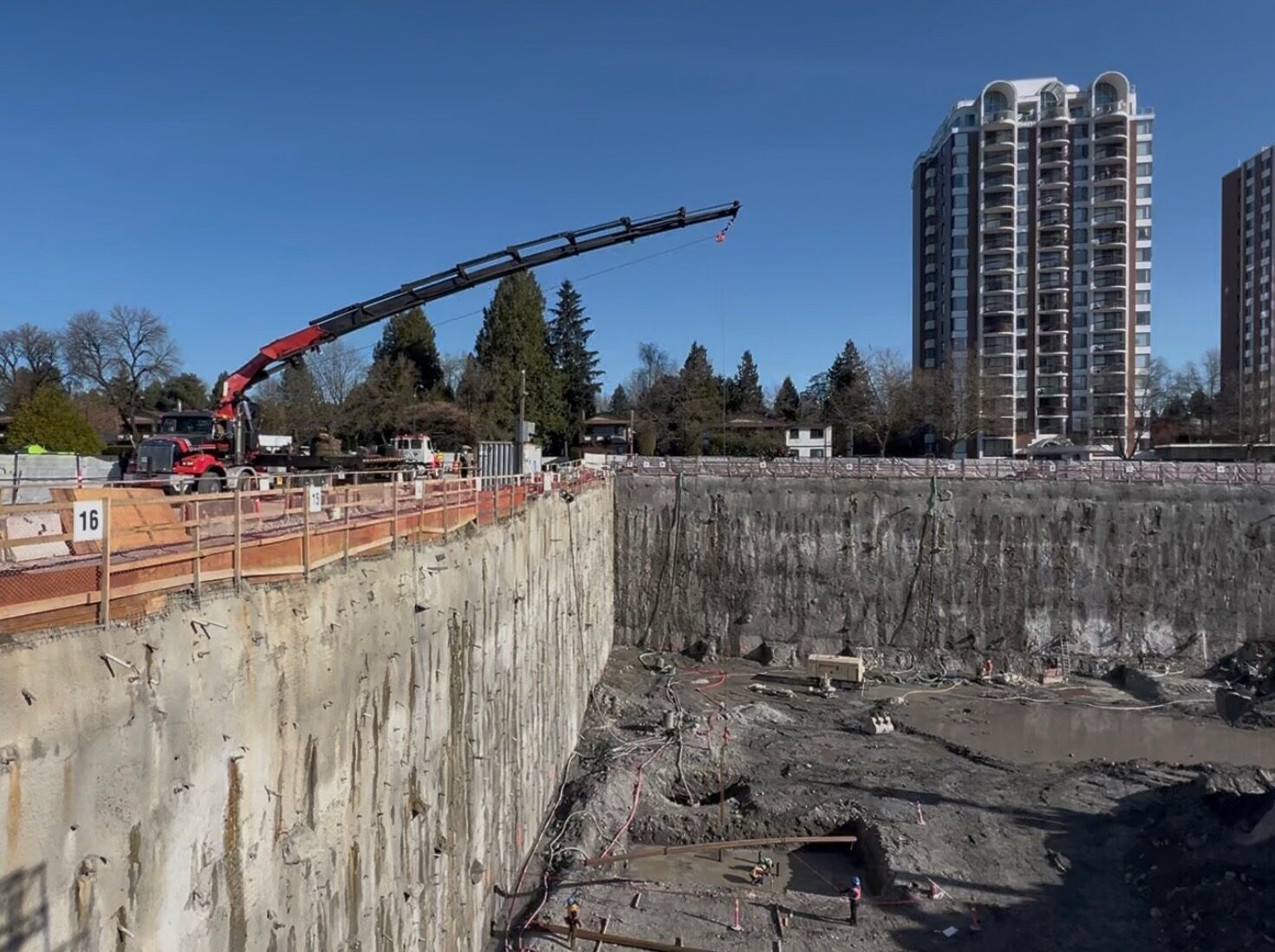 CraneX picker truck lowering material into a deep open excavation