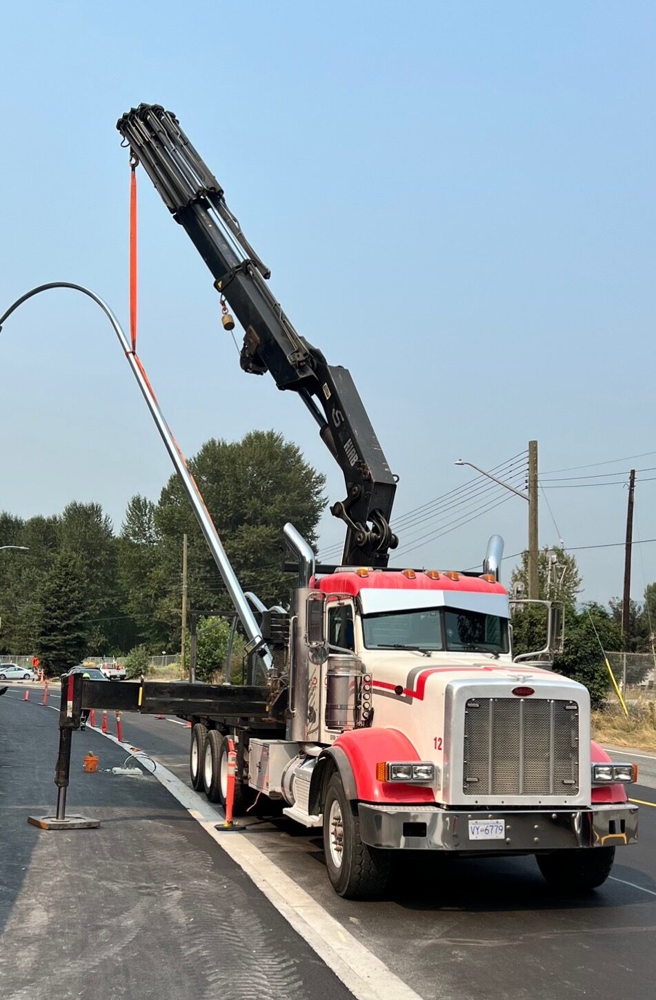 CraneX picker truck installing a street light pole at a roadside site